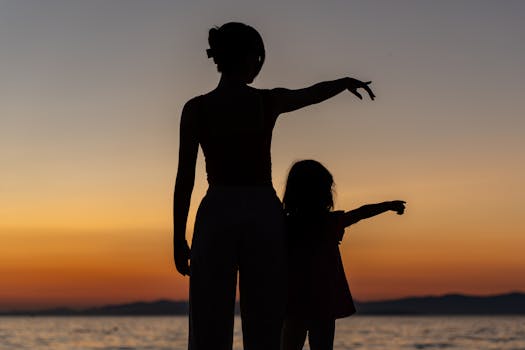 Silhouetted woman and child enjoying a serene sunset by the sea in Supetar.